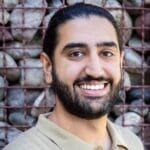 Daanish Tung's headshot smiling with a rock fence background