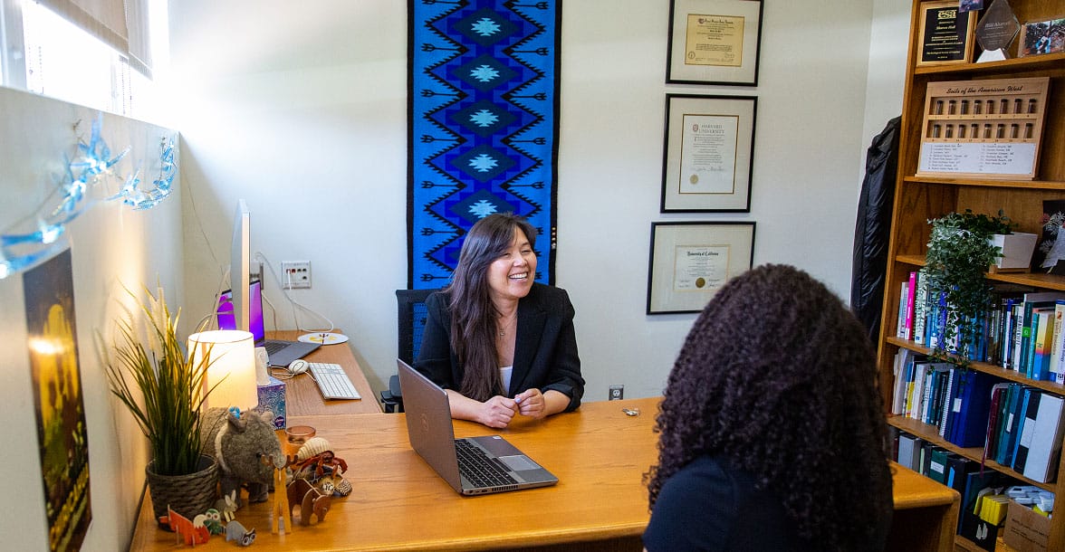 ASU staff member assisting a student at a front desk with brochures and forms, representing access to financial assistance and support services.