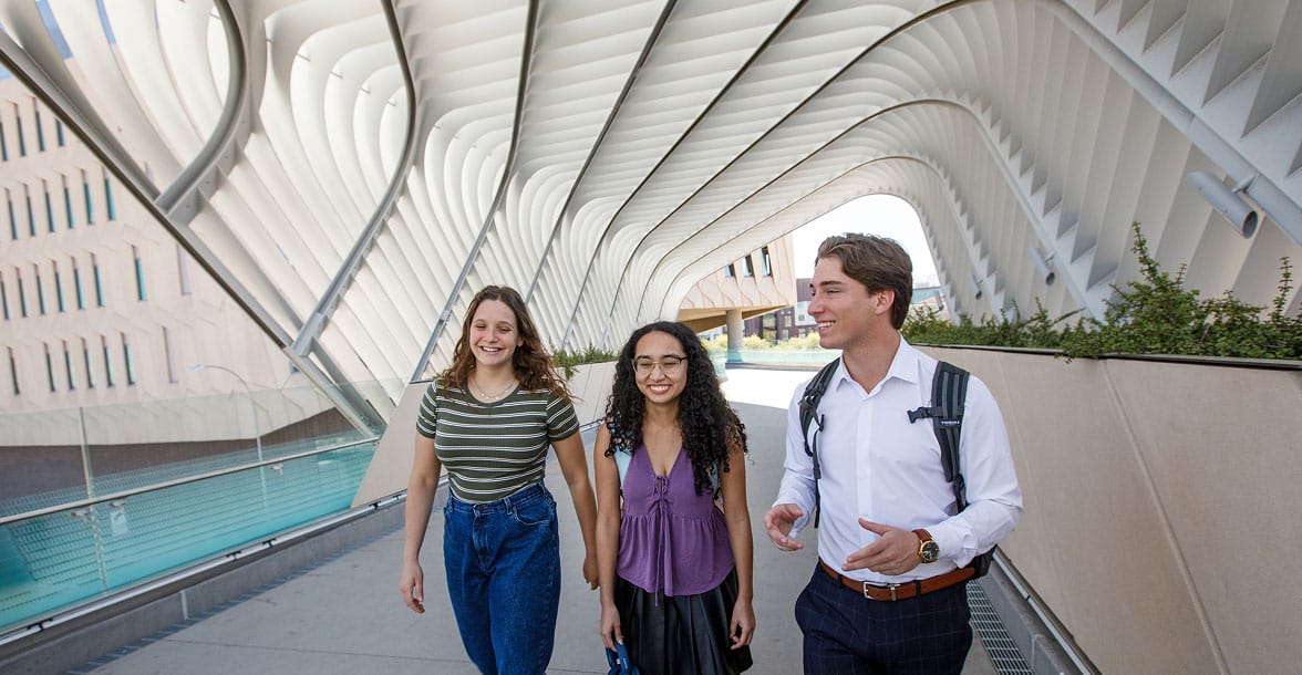 Group of students gathered outdoors at ASU, smiling and talking in a casual, social setting, representing a vibrant campus community.