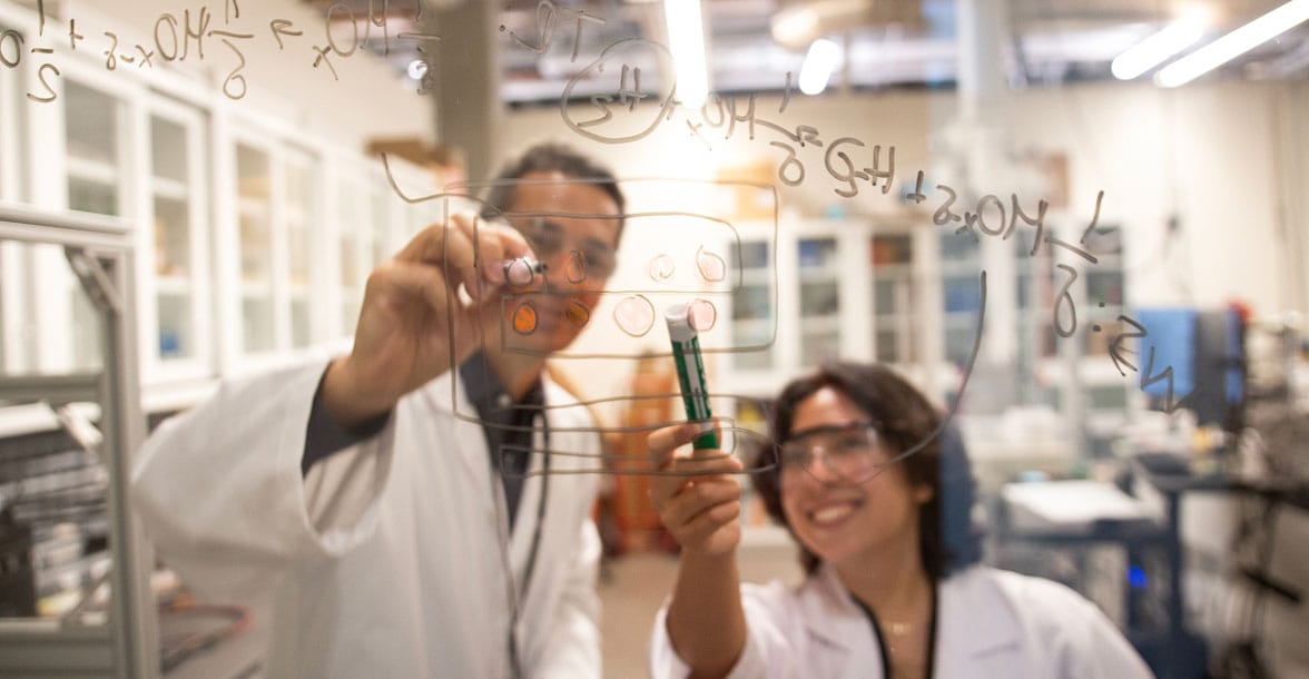 Two researchers in lab coats working with scientific equipment in an ASU laboratory, representing cutting-edge research.